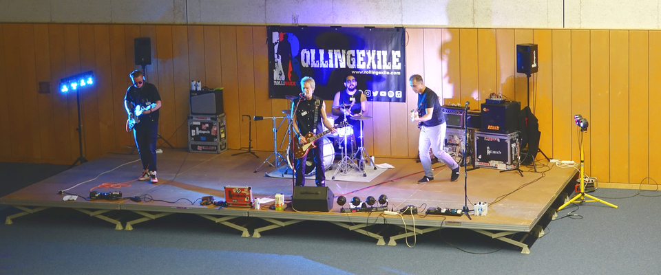 Die vierköpfige Band auf der Bühne in der Mehrzweckhalle unter dem Banner der JVA.